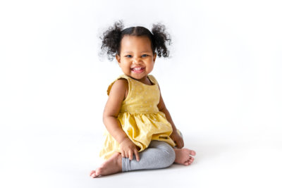 Happy little girl in a yellow dress sitting