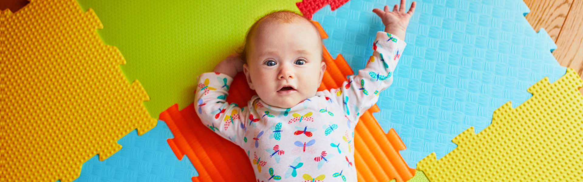 4 months old baby girl lying on colorful play mat